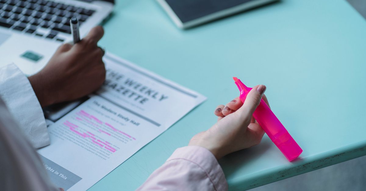 An editor reviewing printed article pages with a pen.